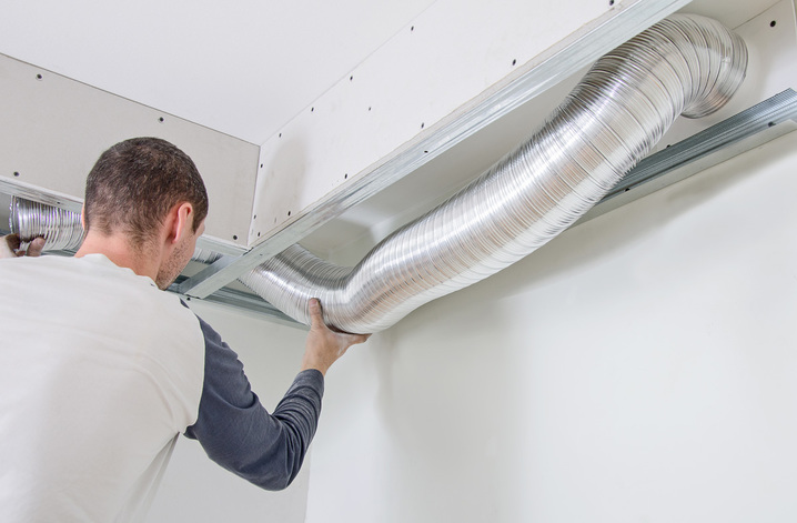 Young male HVAC professional installing ductwork.